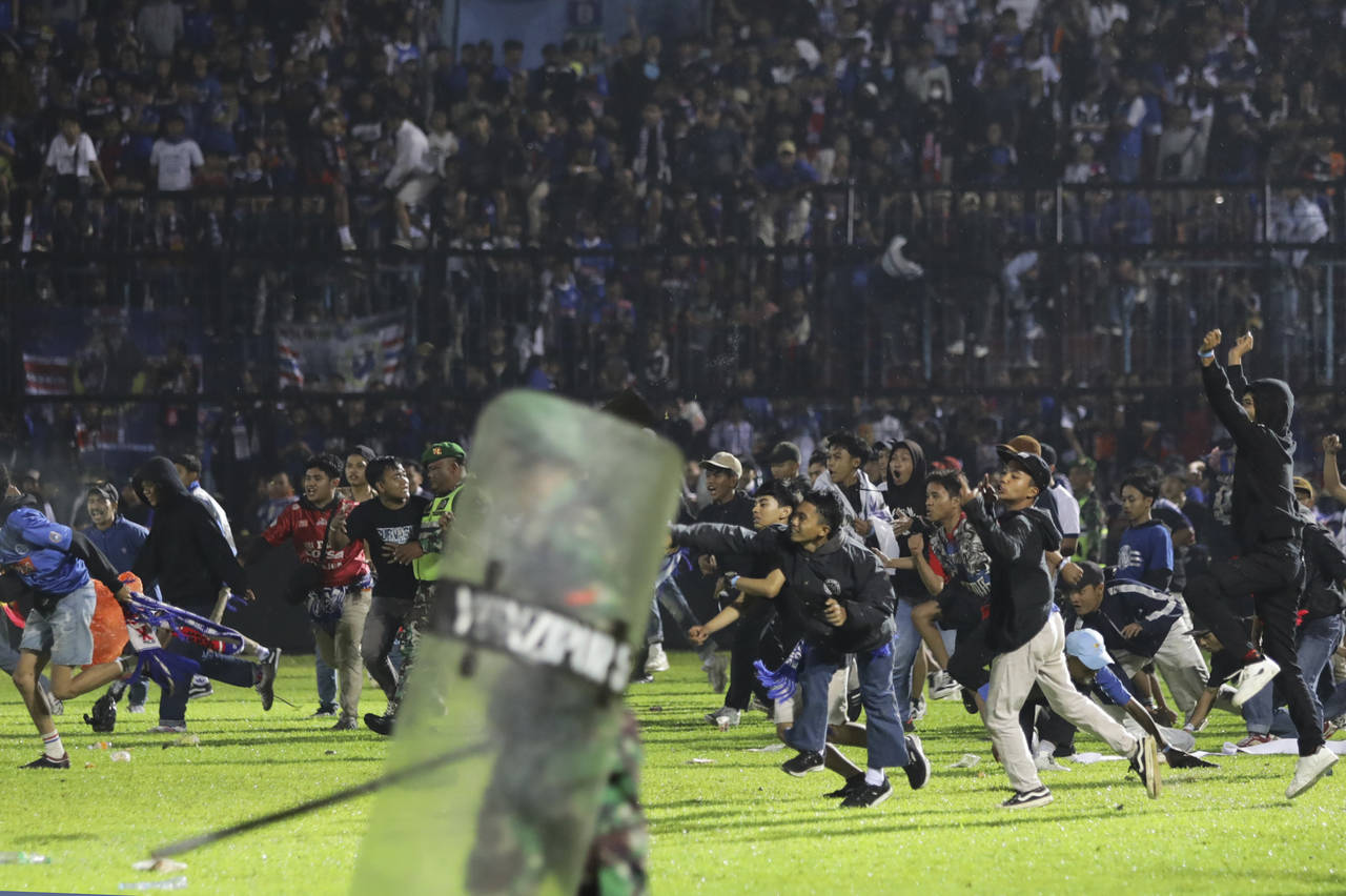 Soccer fans enter the pitch during a clash between supporters at Kanjuruhan Stadium in Malang, East...