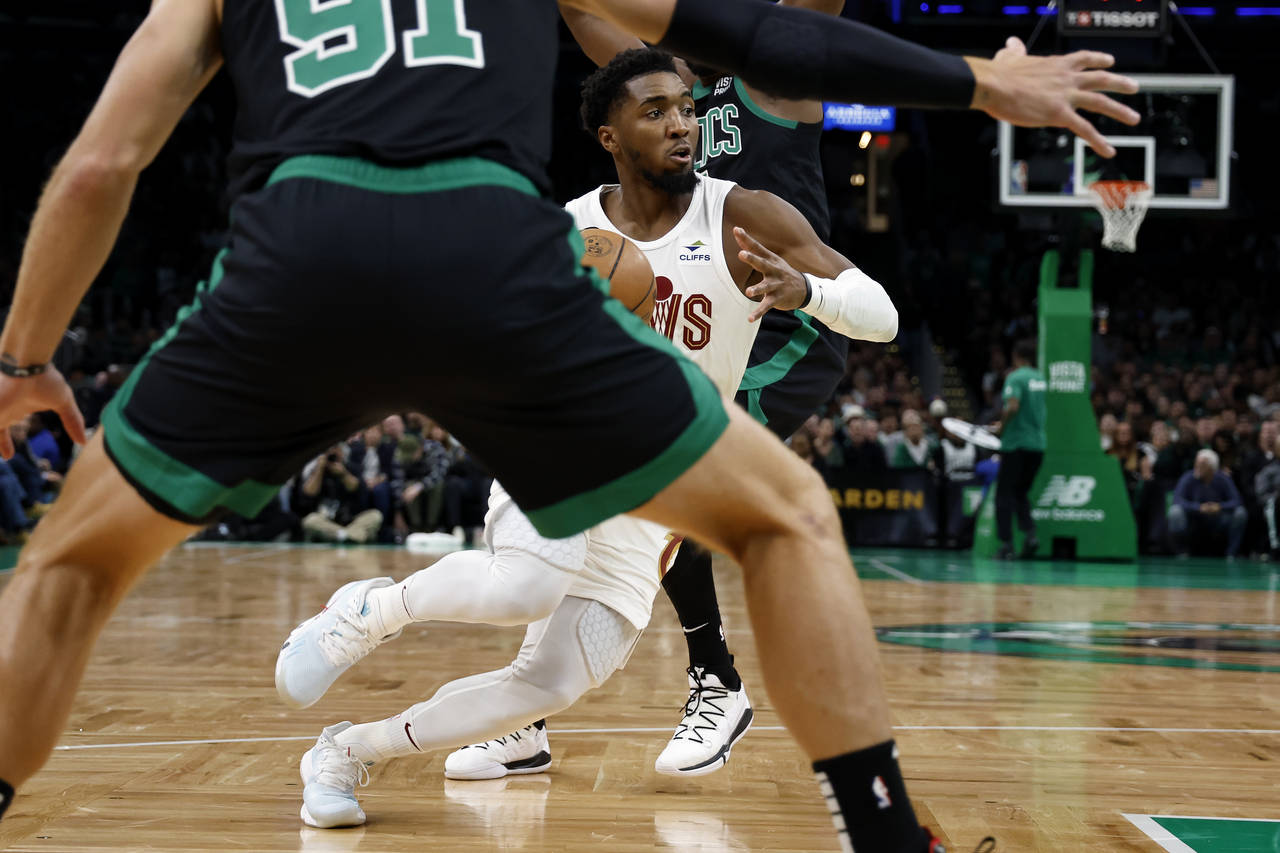 Cleveland Cavaliers' Donovan Mitchell drives between two Boston Celtics defenders during the second...
