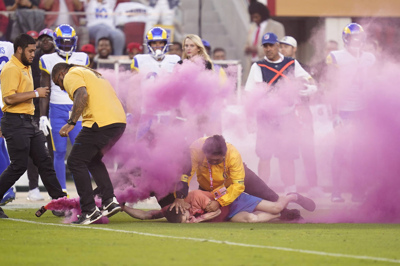 A protester is held down by security after running on the field during the first half of an NFL foo...