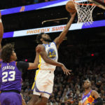 
              Golden State Warriors forward Andrew Wiggins (22) drives between Phoenix Suns guard Damion Lee (10), Cameron Johnson (23), and Chris Paul (3) during the first half of an NBA basketball game, Tuesday, Oct. 25, 2022, in Phoenix. (AP Photo/Rick Scuteri)
            