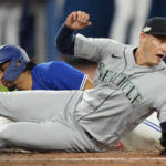 
              Toronto Blue Jays' Santiago Espinal, left, scores on passed ball as Seattle Mariners relief pitcher Paul Sewald, right, tries to defend during the fifth inning of Game 2 of a baseball AL wild-card playoff series Saturday, Oct. 8, 2022, in Toronto. (Frank Gunn/The Canadian Press via AP)
            