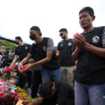 
              Players and officials of the soccer club Arema FC pray outside the Kanjuruhan Stadium where many fans lost their lives in a stampede Saturday night in Malang, Indonesia, Monday, Oct. 3, 2022. Police firing tear gas at Saturday night's match between host Arema FC of East Java's Malang city and Persebaya Surabaya in an attempt to stop violence triggered a disastrous crush of fans making a panicked, chaotic run for the exits, leaving a large number of people dead, most of them trampled upon or suffocated. (AP Photo/Achmad Ibrahim)
            