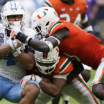 
              North Carolina running back Caleb Hood, left, is taken down by Miami linebacker Corey Flagg Jr. center, and safety James Williams during the first half of an NCAA college football game, Saturday, Oct. 8, 2022, in Miami Gardens, Fla. (AP Photo/Wilfredo Lee)
            