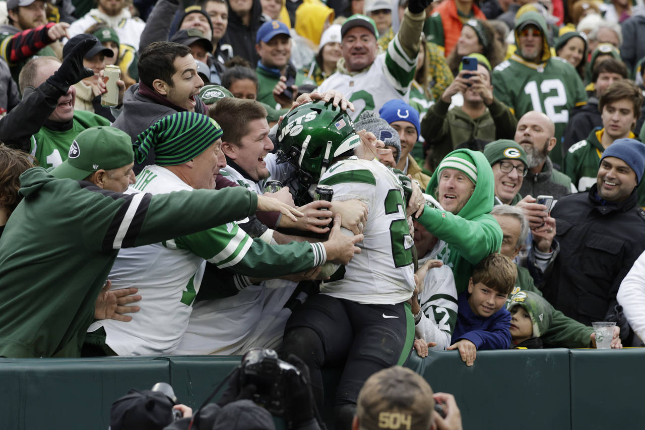 New York Jets running back Breece Hall jumps into the Jets' fans area to celebrate his 34-yard rush...