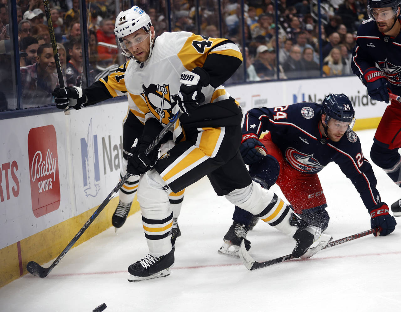 Pittsburgh Penguins defenseman Jan Rutta, left, reaches for the puck in front of Columbus Blue Jack...