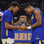 
              Golden State Warriors' Stephen Curry presents teammate Jordan Poole with a trophy for the best free throw percentage in the NBA last season before the start of their preseason NBA game against the Los Angeles Lakers in San Francisco, on Sunday, Oct. 9, 2022. (Jose Carlos Fajardo/Bay Area News Group via AP)
            