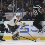 
              An official jumps out of the way as Seattle Kraken defenseman Jamie Oleksiak (24) and Vegas Golden Knights center Jack Eichel go for the puck during the first period of an NHL hockey game Saturday, Oct. 15, 2022, in Seattle. (AP Photo/Jason Redmond)
            