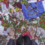
              A man prays near flowers laid at the Kanjuruhan Stadium where a soccer stampede killed more than 100 people on Oct. 1, in Malang, East Java, Indonesia, Saturday, Oct. 8, 2022. Indonesia's president said the country will not face sanctions from soccer's world governing body and will remain the host of next year's U-20 World Cup after the firing of tear gas after a match inside the half-locked stadium caused the deadly crush at the exits. (AP Photo/Dicky Bisinglasi)
            