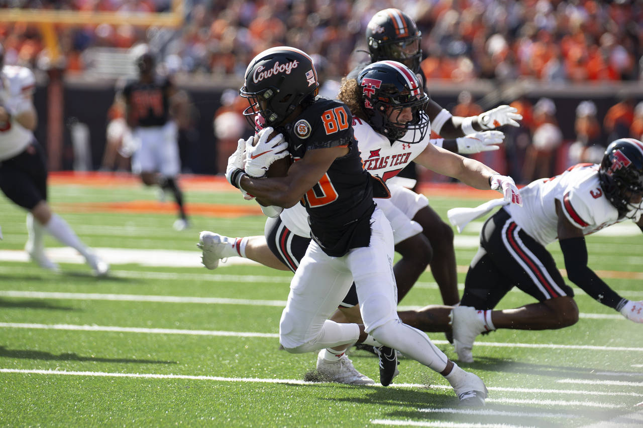 Oklahoma State's Brennan Presley (80) breaks a tackle by Texas Tech's Patrick Curley during the fir...