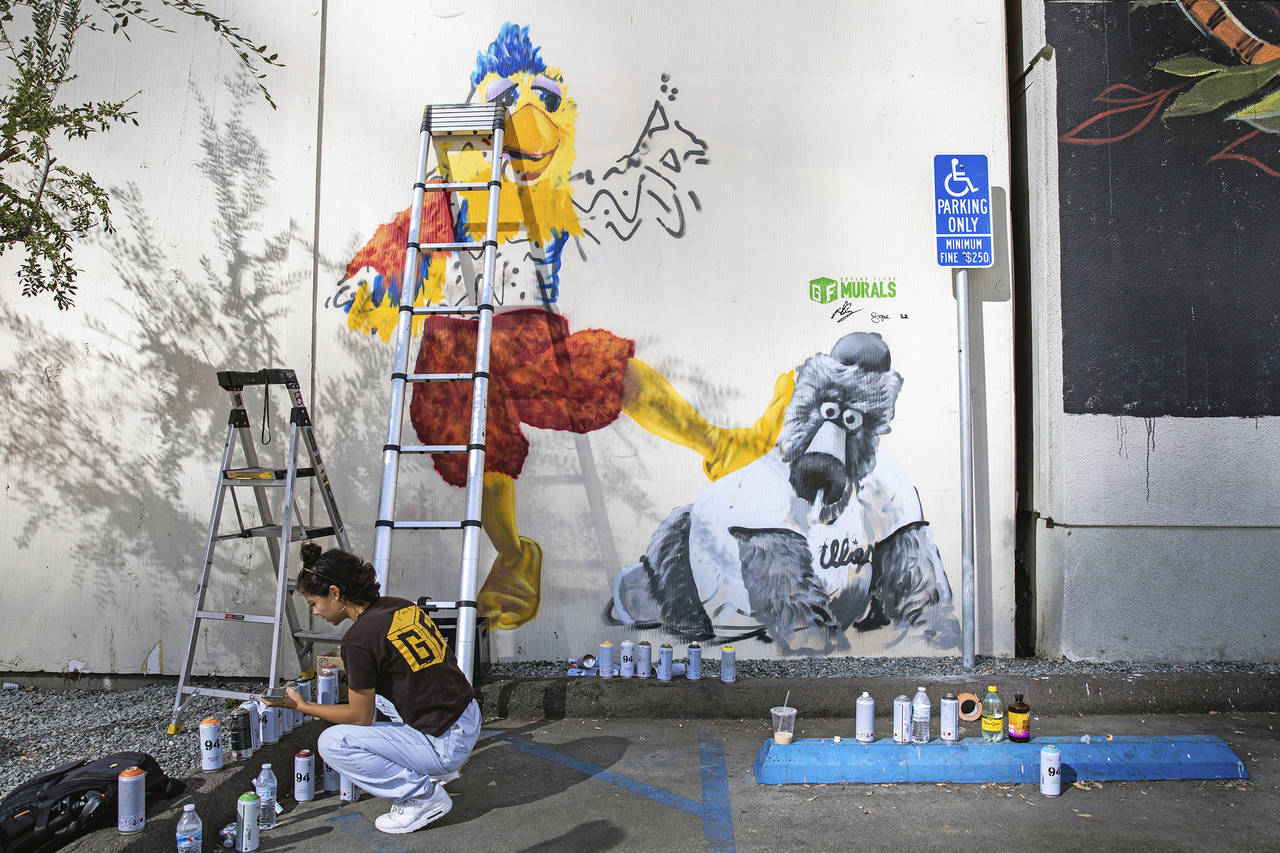 Ground Floor Murals artist Signe Ditona works on a mural of the San Diego Chicken mascot stomping o...