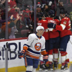 
              Florida Panthers' Anton Lundell (15) celebrates with teammates and fans after scoring a goal as New York Islanders' Ryan Pulock, foreground, skates past during the first period of an NHL hockey game, Sunday, Oct. 23, 2022, in Sunrise, Fla. (AP Photo/Michael Laughlin)
            