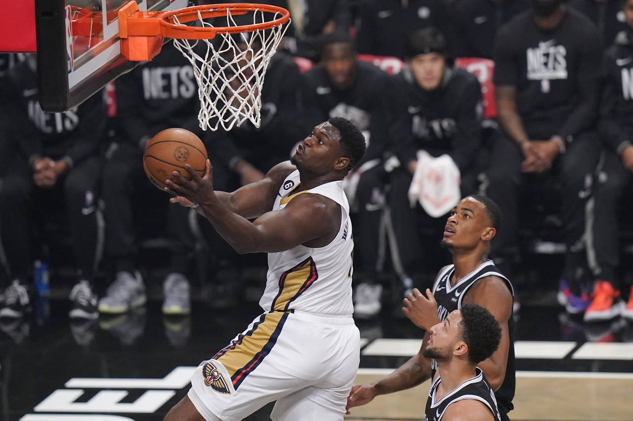 New Orleans Pelicans' Zion Williamson, left, drives past Brooklyn Nets' Nic Claxton, top right, and...