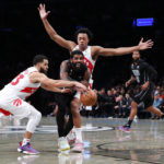 
              Brooklyn Nets guard Kyrie Irving (11) drives to the basket against Toronto Raptors guard Fred VanVleet (23) and forward Scottie Barnes during the second half of an NBA basketball game Friday, Oct. 21, 2022, in New York. (AP Photo/Noah K. Murray)
            