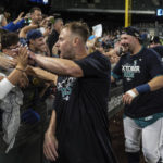 
              Seattle Mariners, including Jarred Kelenic, foreground, Cal Raleigh, second from left, and another player celebrate with fans after the team's baseball game against the Oakland Athletics, Friday, Sept. 30, 2022, in Seattle. The Mariners won 2-1 to clinch a spot in the playoffs. (AP Photo/Stephen Brashear)
            