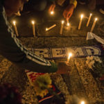 
              Soccer fans light candles during a vigil for supporters of Arema FC who died in Saturday's stampede, in Medan, North Sumatra, Indonesia, Monday, Oct. 3, 2022. Indonesian police said they were investigating over a dozen officers responsible for firing tear gas that set off a crush that killed a number of people at a soccer match between Arema FC of Malang and Persebaya of neighboring Surabaya city, as families and friends grieved Monday for the victims that included children. (AP Photo/Binsar Bakkara)
            