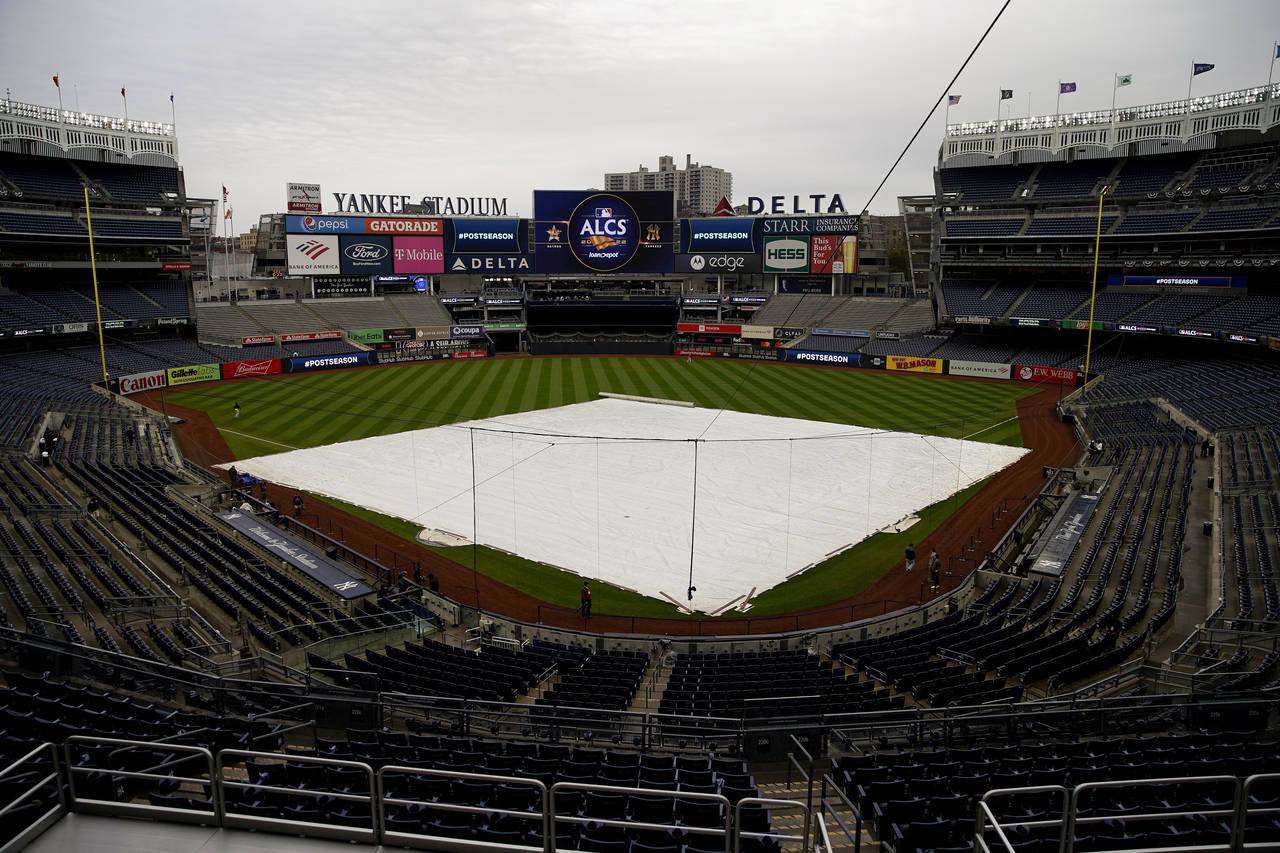 The rain tarp covers the field as a light rain falls on Yankee Stadium before Game 4 of an American...