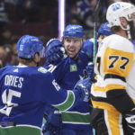 
              Vancouver Canucks' Tanner Pearson (70), Sheldon Dries (15) and Ilya Mikheyev, back right, of Russia, celebrate Pearson's goal as Pittsburgh Penguins' Jeff Carter (77) skates past during the first period of an NHL hockey game in Vancouver, British Columbia on Friday, Oct. 28, 2022. (Darryl Dyck/The Canadian Press via AP)
            