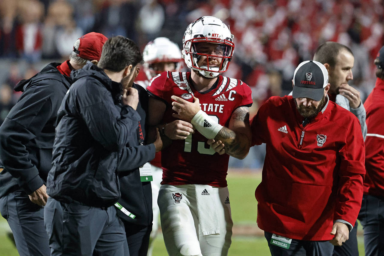 North Carolina State quarterback Devin Leary (13) is assisted off the field by medical staff during...
