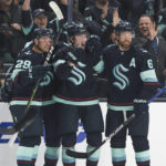 
              Seattle Kraken center Morgan Geekie, center, celebrates with teammates Vince Dunn (29) and Adam Larsson (6) after scoring a goal during the first period of an NHL hockey game against the Buffalo Sabres, Tuesday, Oct. 25, 2022, in Seattle. (AP Photo/Jason Redmond)
            