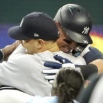 
              New York Yankees' Aaron Judge, right, hugs teammates after hitting a solo home run, his 62nd of the season, during the first inning in the second baseball game against the Texas Rangers in Arlington, Texas, Tuesday, Oct. 4, 2022. With the home run, Judge set the AL record for home runs in a season, passing Roger Maris. (AP Photo/LM Otero)
            