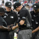 
              MLB Network's Kelvin Pickens, left, inspects radio and headset for a call on a play review with umpires Cory Blaser, second from left, Edwin Moscoso, right, and Dan Bellino after the first inning of a baseball game in Chicago, Friday, July 22, 2022. After a century and a half of Major League Baseball — after generations of grunts and growls, of muffled shouts and dramatic arm gestures and a cultivated sense of remoteness — something quietly extraordinary happened to the national pastime this year: The umpires began talking to the world. (AP Photo/Nam Y. Huh)
            