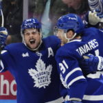
              Toronto Maple Leafs' William Nylander, obscured, celebrates his goal against the Ottawa Senators with Auston Matthews, left, and John Tavares (91) during the third period of an NHL hockey game Saturday, Oct. 15, 2022, in Toronto. (Frank Gunn/The Canadian Press via AP)
            