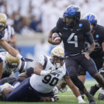 
              Air Force quarterback Haaziq Daniels, right, evades Navy defensive lineman Donald Berniard Jr., center, and linebacker Colin Ramos for a short gain in the second half of an NCAA college football game Saturday, Oct. 1, 2022, at Air Force Academy, Colo. (AP Photo/David Zalubowski)
            