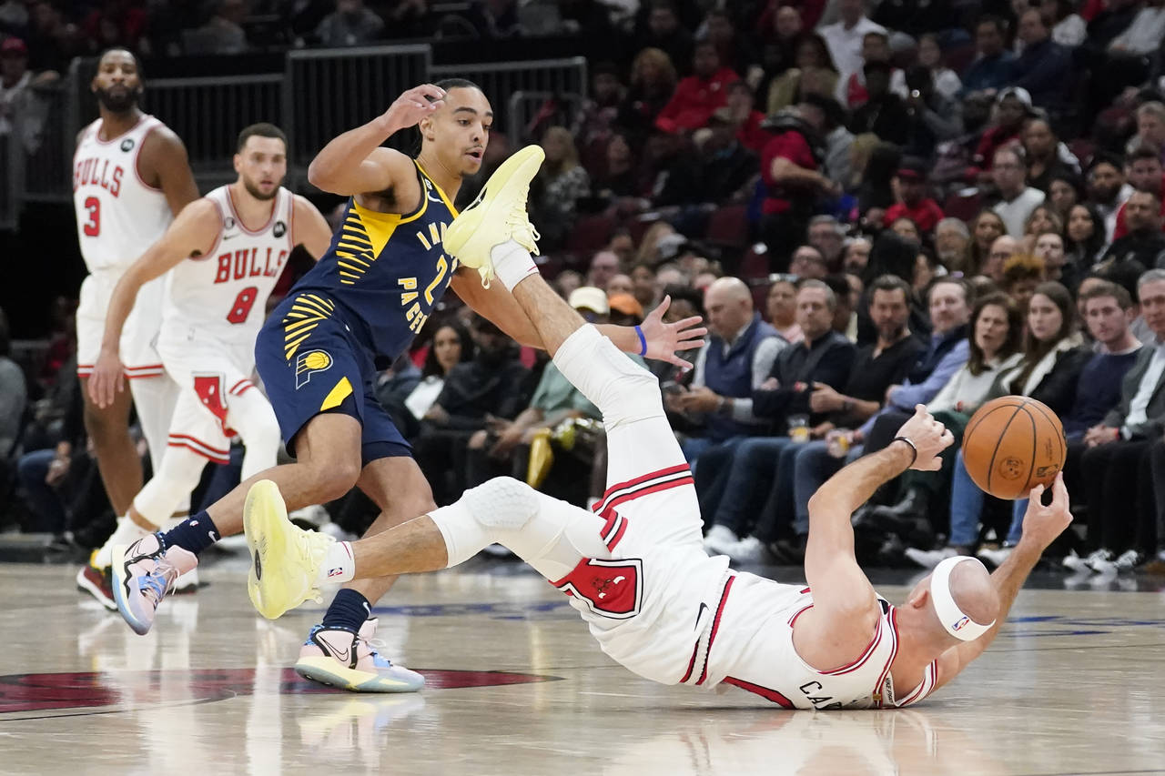 Chicago Bulls' Alex Caruso tries to control a loose ball as Indiana Pacers' Andrew Nembhard watches...