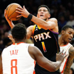 
              Phoenix Suns' Devin Booker (1) drives to the basket between Houston Rockets' Jae'Sean Tate (8) and Kevin Porter Jr. (3) during the second half of an NBA basketball game, Sunday, Oct. 30, 2022, in Phoenix. (AP Photo/Darryl Webb)
            