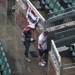 
              People cover up from rain in Truist Park before Game 2 of baseball's National League Division Series between the Atlanta Braves and the Philadelphia Phillies, Wednesday, Oct. 12, 2022, in Atlanta. The game has been rain delayed. (AP Photo/Brynn Anderson)
            