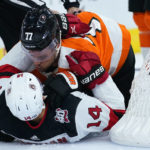 
              Philadelphia Flyers' Tony DeAngelo (77) and New Jersey Devils' Nathan Bastian (14) wrestle during the first period of an NHL hockey game, Thursday, Oct. 13, 2022, in Philadelphia. (AP Photo/Matt Slocum)
            