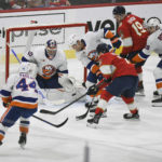 
              New York Islanders' Ryan Pulock, center, stops the puck in front of Florida Panthers' Sam Reinhart during the first period of an NHL hockey game, Sunday, Oct. 23, 2022, in Sunrise, Fla. (AP Photo/Michael Laughlin)
            