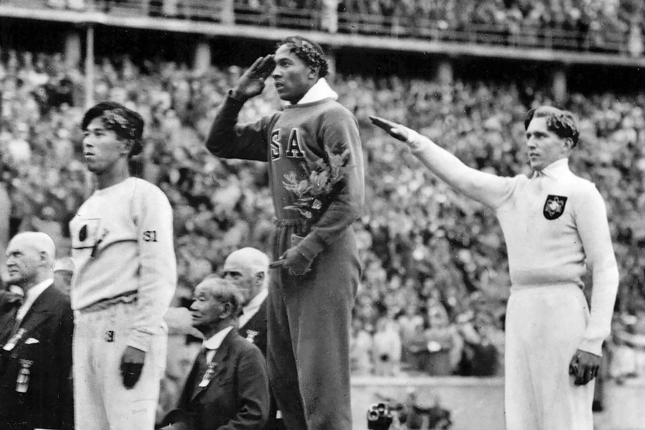 FILE - In this Aug. 11, 1936, file photo, America's Jesse Owens, center, salutes during the present...