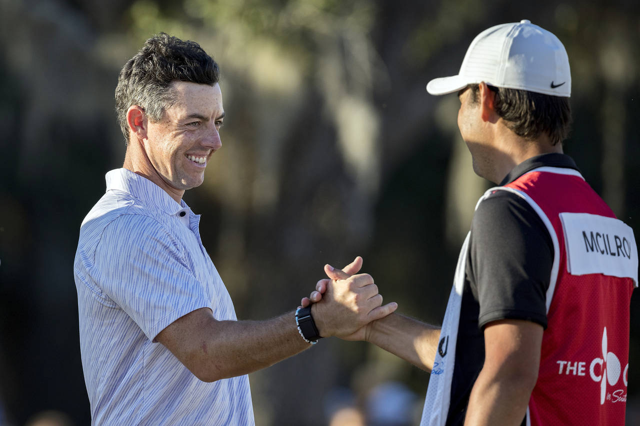 Rory McIlroy, left, of Northern Ireland, left, celebrates with his caddie after the final round of ...