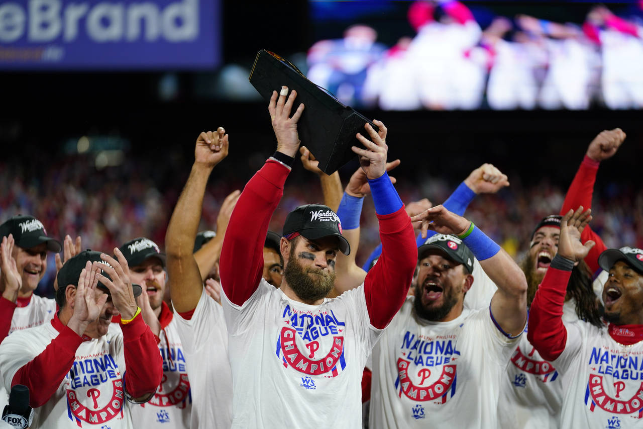 Philadelphia Phillies designated hitter Bryce Harper celebrates with the trophy after winning the b...