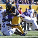 
              West Virginia tight end CJ Donaldson (12) is tackled TCU cornerback Josh Newton (24) and safety Namdi Obiazor (4) during the first half of an NCAA college football game in Morgantown, W.Va., Saturday, Oct. 29, 2022. (AP Photo/Kathleen Batten)
            