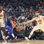 
              New York Knicks forward Julius Randle, second from left, grabs the ball against Cleveland Cavaliers forward Dean Wade (32) during the first half of an NBA basketball game, Sunday, Oct. 30, 2022, in Cleveland. (AP Photo/Nick Cammett)
            