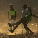 
              FILE- Young boys play soccer on a dusty field in Duduza, east of Johannesburg, South Africa, June 23, 2021. Soccer has embarked on probably its most ambitious global youth development program, an ultimate goal of delivering millions of soccer balls and a coaching program to 700 million children aged between 4 and 14 across the world. The Football For Schools project was launched in 2019 but came to a grinding halt because of the COVID-19 pandemic. It has now been relaunched. (AP Photo/Themba Hadebe, File)
            