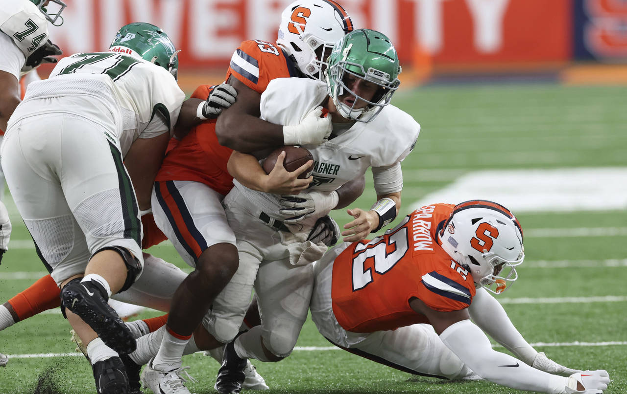 Wagner quarterback Ryan Kraft (7) is brought down behind the line of scrimmage by Syracuse defender...