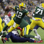 
              Green Bay Packers quarterback Aaron Rodgers (12) breaks a tackle by New England Patriots linebacker Matthew Judon (9) during overtime in an NFL football game, Sunday, Oct. 2, 2022, in Green Bay, Wis. The Packers won 27-24. (AP Photo/Mike Roemer)
            
