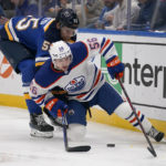 
              Edmonton Oilers' Kailer Yamamoto (56) and St. Louis Blues' Colton Parayko (55) chase after a loose puck along the boards during the third period of an NHL hockey game Wednesday, Oct. 26, 2022, in St. Louis. (AP Photo/Jeff Roberson)
            