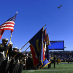 
              Midshipman hold flags during the playing of the national anthem as two Navy F18 aircrafts perform a flyover prior to an NCAA college football game between Navy and Temple, Saturday, Oct. 29, 2022, in Annapolis, Md. (AP Photo/Terrance Williams)
            