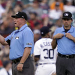 
              Umpire Marvin Hudson, left, makes the call after a review with umpire John Tumpane during the fifth inning of a baseball game between the Detroit Tigers and the Minnesota Twins, Saturday, July 23, 2022, in Detroit. A rule change at the beginning of the season designed to explain on-field call challenges and outcomes introduced umpires’ voices to ballpark speakers, to the fans in their seats and to the world at home for the first time. (AP Photo/Carlos Osorio)
            