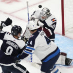 
              Colorado Avalanche goaltender Alexandar Georgiev, back, stops a shot as center Evan Rodrigues, front left, and Winnipeg Jets defenseman Neal Pionk work for position in front of the net during the first period of an NHL hockey game Wednesday, Oct. 19, 2022, in Denver. (AP Photo/David Zalubowski)
            