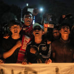 
              Soccer fans chant slogans during a candle light vigil for the victims of Saturday's soccer riots, in Jakarta, Indonesia, Sunday, Oct. 2, 2022. Panic and a chaotic run for exits after police fired tear gas at an Indonesian soccer match in East Java to drive away fans upset with their team's loss left a large number of people dead, most of whom were trampled upon or suffocated. (AP Photo/Dita Alangkara)
            