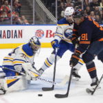 
              Buffalo Sabres goalie Eric Comrie (31) makes a save on Edmonton Oilers' Evander Kane (91) as Mattias Samuelsson (23) defends during the second period of an NHL hockey game Tuesday, Oct. 18, 2022, in Edmonton, Alberta. (Jason Franson/The Canadian Press via AP)
            