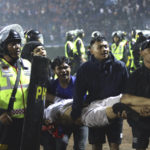 
              Soccer fans carry an injured man following clashes during a soccer match at Kanjuruhan Stadium in Malang, East Java, Indonesia, Saturday, Oct. 1, 2022. Panic following police actions left over 100 dead, mostly trampled to death, police said Sunday. (AP Photo/Yudha Prabowo)
            