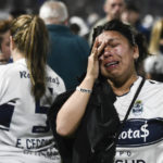 
              Fans of Gimnasia de La Plata react to tear gas on the field during a local tournament match between Gimnasia de La Plata and Boca Juniors in La Plata, Argentina, Thursday, Oct. 6, 2022. The match was suspended after tear gas thrown by the police outside the stadium wafted inside affecting the players as well as fans who fled to the field to avoid its effects. (AP Photo/Gustavo Garello)
            