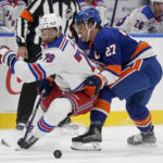 
              New York Rangers defenseman K'Andre Miller (79) and New York Islanders left wing Anders Lee (27) battle for the puck in the second period of an NHL hockey game, Wednesday, Oct. 26, 2022, in Elmont, N.Y. (AP Photo/John Minchillo)
            