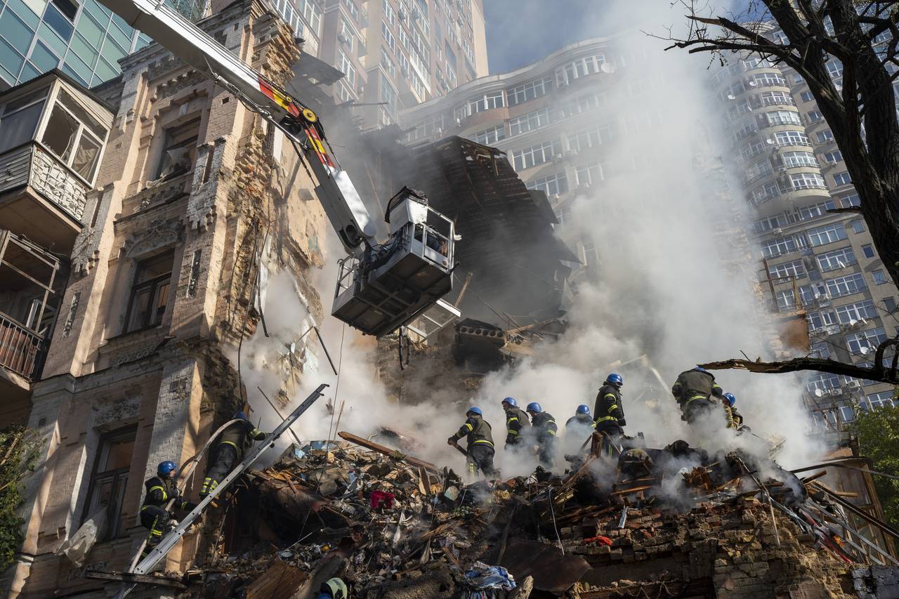 FILE - Firefighters work after a drone attack on buildings in Kyiv, Ukraine, Oct. 17, 2022. Waves o...
